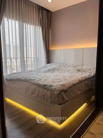 Cozy bedroom with modern lighting and large windows in a stylish apartment.