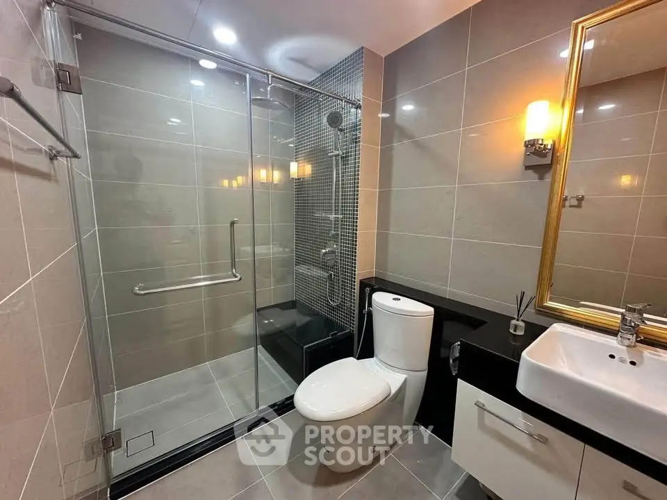 Modern bathroom with glass shower, sleek tiles, and elegant lighting