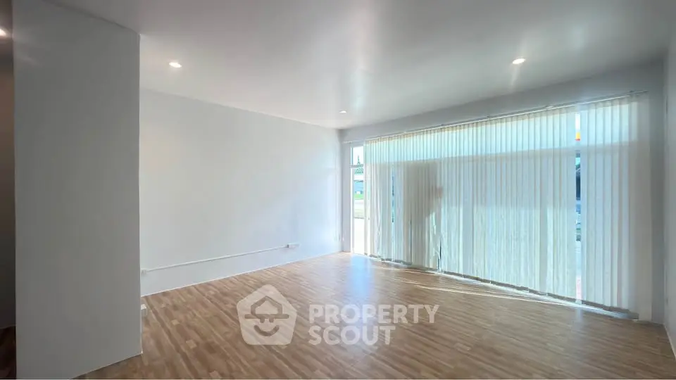 Spacious living room with large windows and wooden flooring, perfect for natural light lovers.