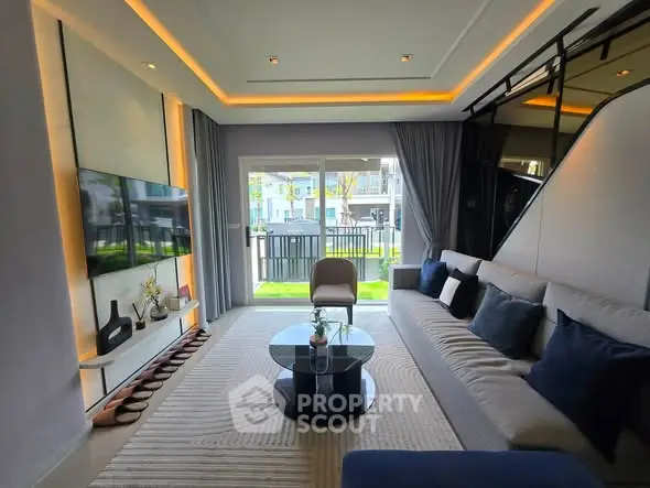 Modern living room with stylish decor, large windows, and cozy seating area overlooking a garden.
