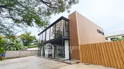 Modern minimalist two-story building with glass facade and wooden accents.