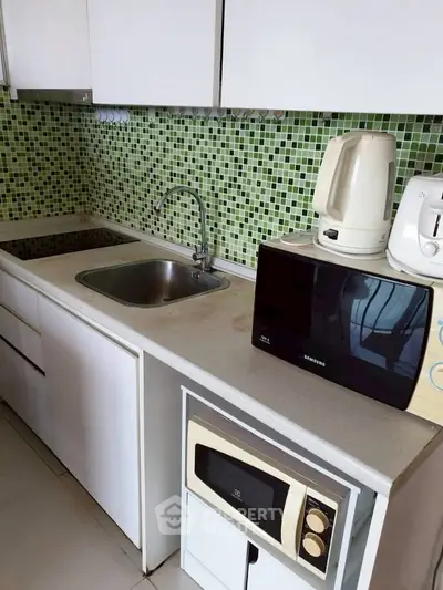 Modern kitchen with sleek appliances and stylish green mosaic backsplash.