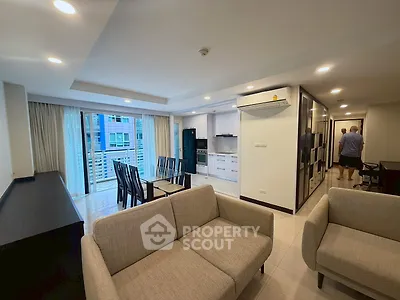 Spacious modern living room with open kitchen and large windows in a high-rise apartment.