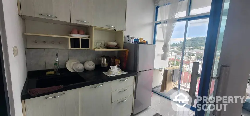 Charming kitchen with balcony view, featuring modern cabinetry and natural light.