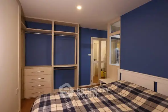 Spacious bedroom with built-in closet and modern blue accent wall.