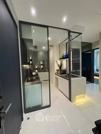 Modern kitchen with sleek design and open layout, featuring glass partitions and contemporary lighting.
