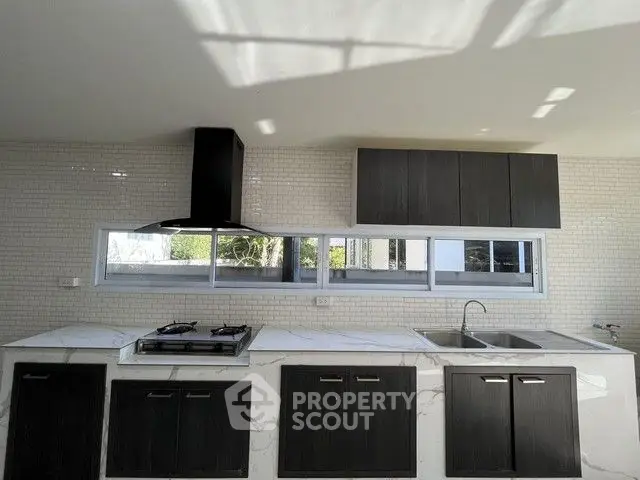 Modern kitchen with sleek cabinetry and gas stove in bright natural light.