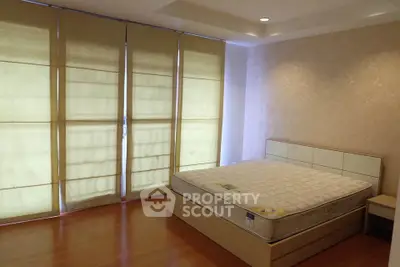 Spacious bedroom with large windows and modern decor, featuring a comfortable bed and stylish blinds.