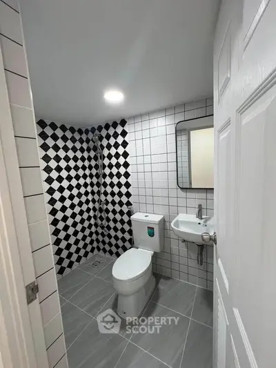 Modern bathroom with stylish black and white tiles and sleek fixtures.