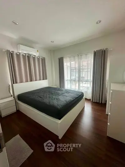 Spacious bedroom with large windows and modern furnishings, perfect for comfortable living.