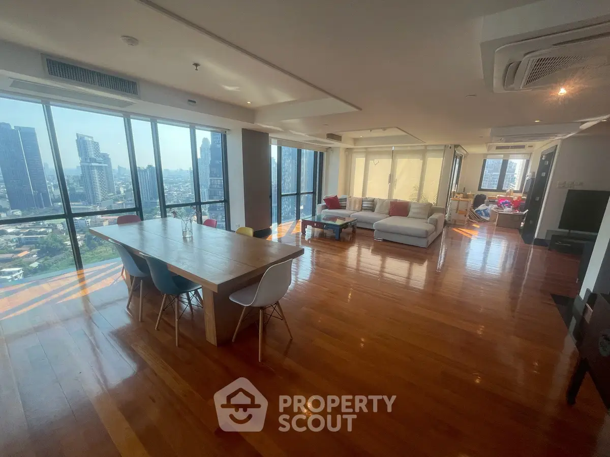 Spacious modern living room with panoramic city views and elegant wooden flooring.