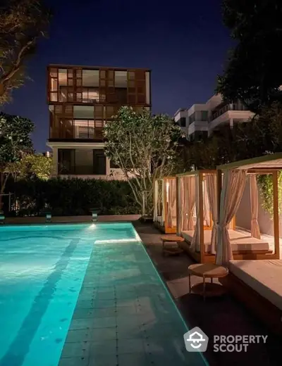 Luxurious night view of modern apartment with illuminated pool and cabanas