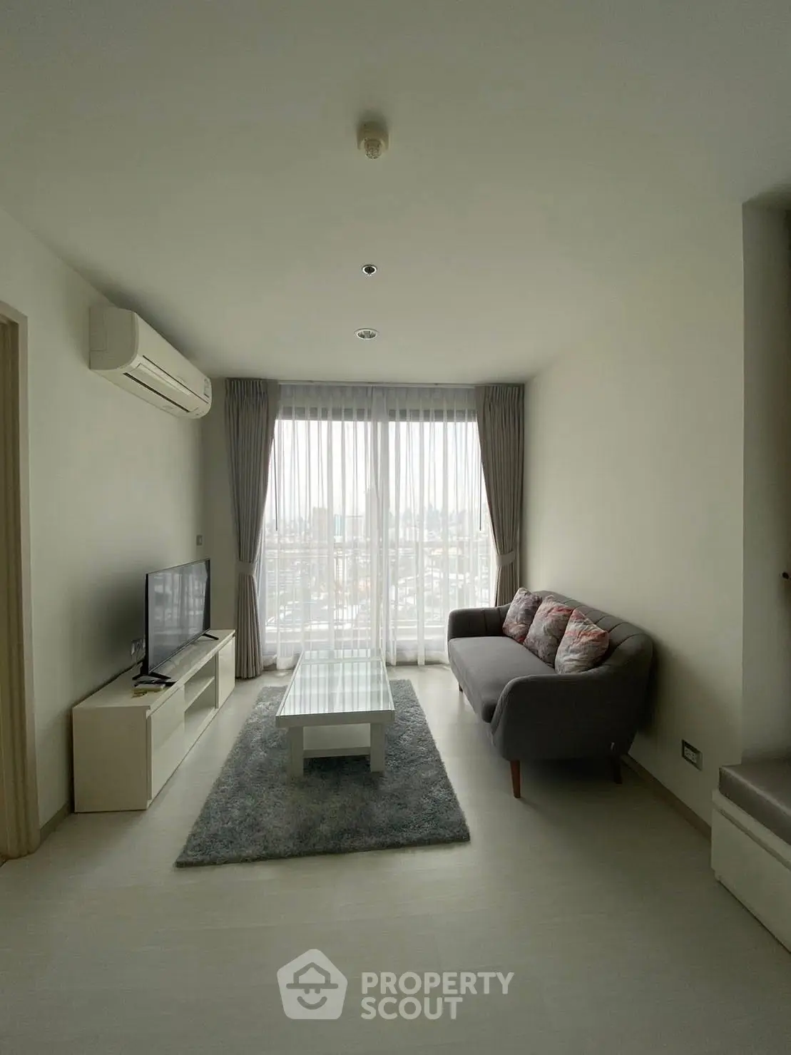 Modern living room with city view, featuring sleek furniture and large windows for natural light.