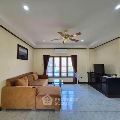 Spacious living room with cozy sofa and ceiling fan, perfect for relaxation.