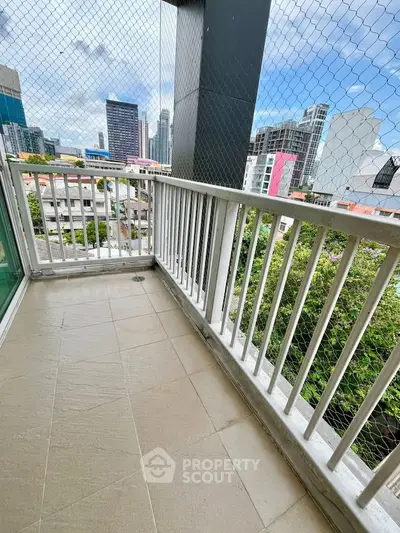 Spacious balcony with city view and safety netting, perfect for relaxation.