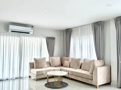 Bright and spacious living room with modern beige sofa and elegant curtains
