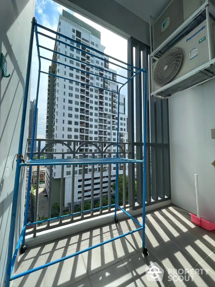 Modern high-rise balcony with city view and laundry rack, perfect for urban living.