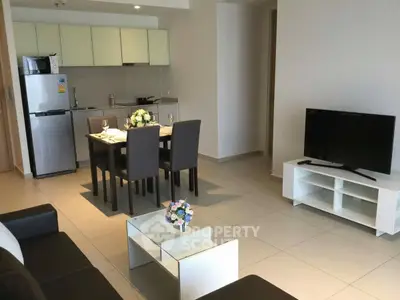 Modern open-plan living room with sleek kitchen and dining area, featuring contemporary furniture and decor.