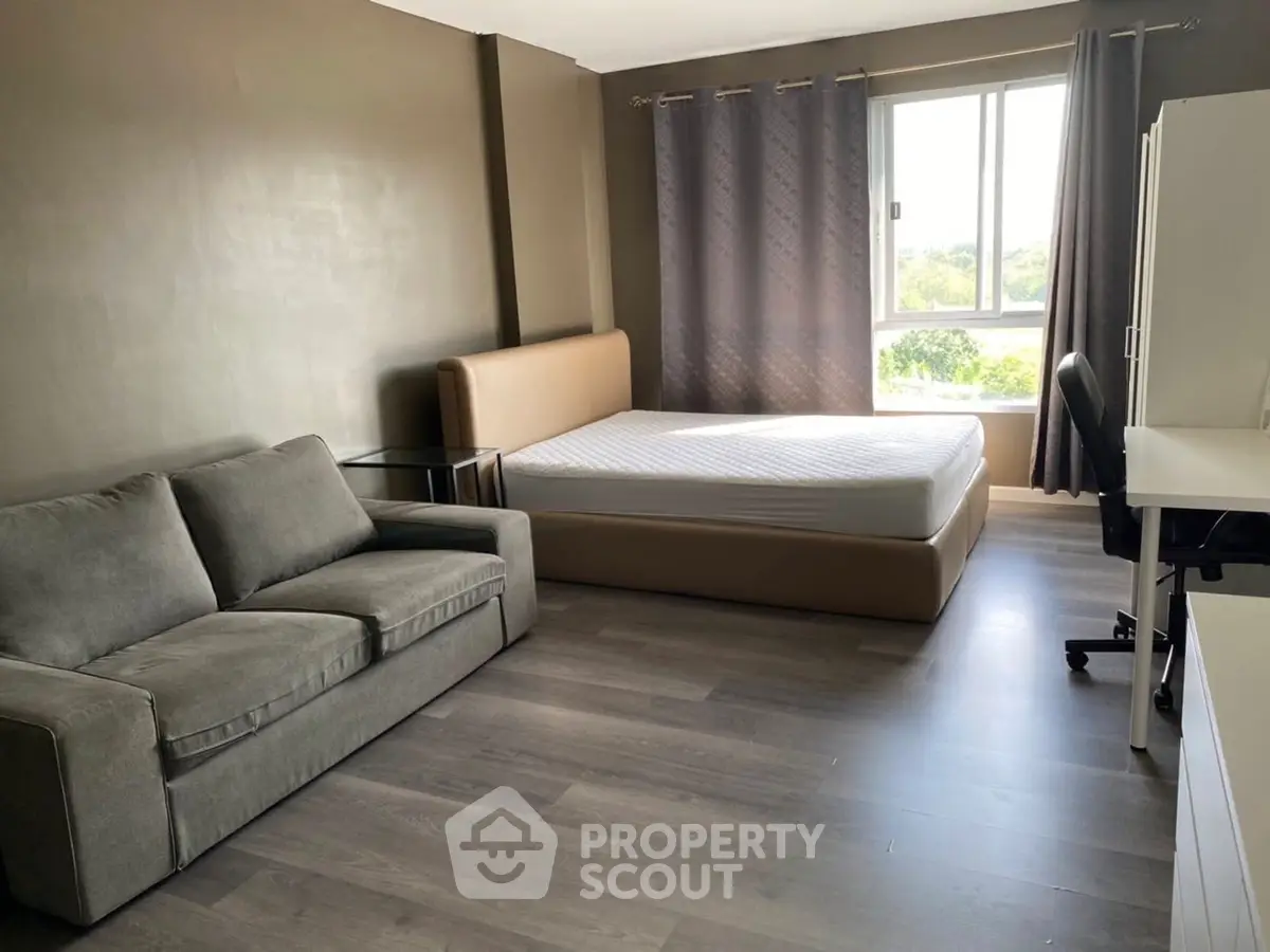 Spacious studio apartment with modern furnishings and large window view.