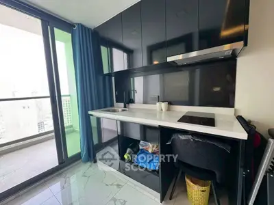 Modern kitchen with sleek black cabinets and balcony access in a stylish apartment.