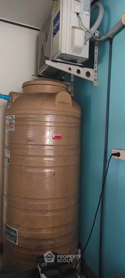 Utility room with large water tank and air conditioning unit, ideal for efficient home management.