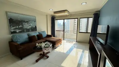 Spacious living room with city view and modern decor in high-rise apartment.