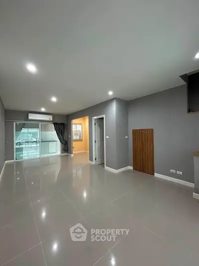 Spacious modern living room with sleek tile flooring and large windows for natural light.