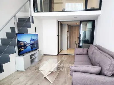 Modern duplex living room with sleek staircase and large TV, perfect for urban living.