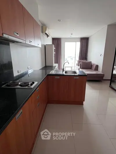 Modern kitchen with sleek cabinetry and open layout leading to a cozy living area with natural light.