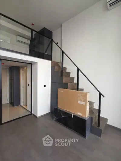 Modern duplex apartment with sleek staircase and high ceilings, featuring a new appliance box.