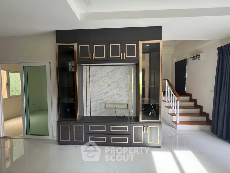 Spacious modern living room with elegant built-in shelving and staircase, perfect for stylish living.