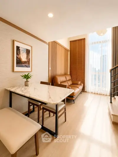 Modern living room with elegant marble dining table and cozy seating area, featuring large windows for natural light.