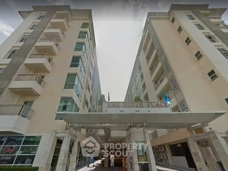 Modern apartment building entrance with sleek design and spacious balconies.