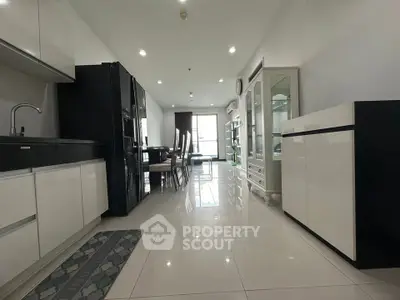 Spacious modern living area with sleek kitchen and dining space, featuring glossy white cabinets and elegant decor.