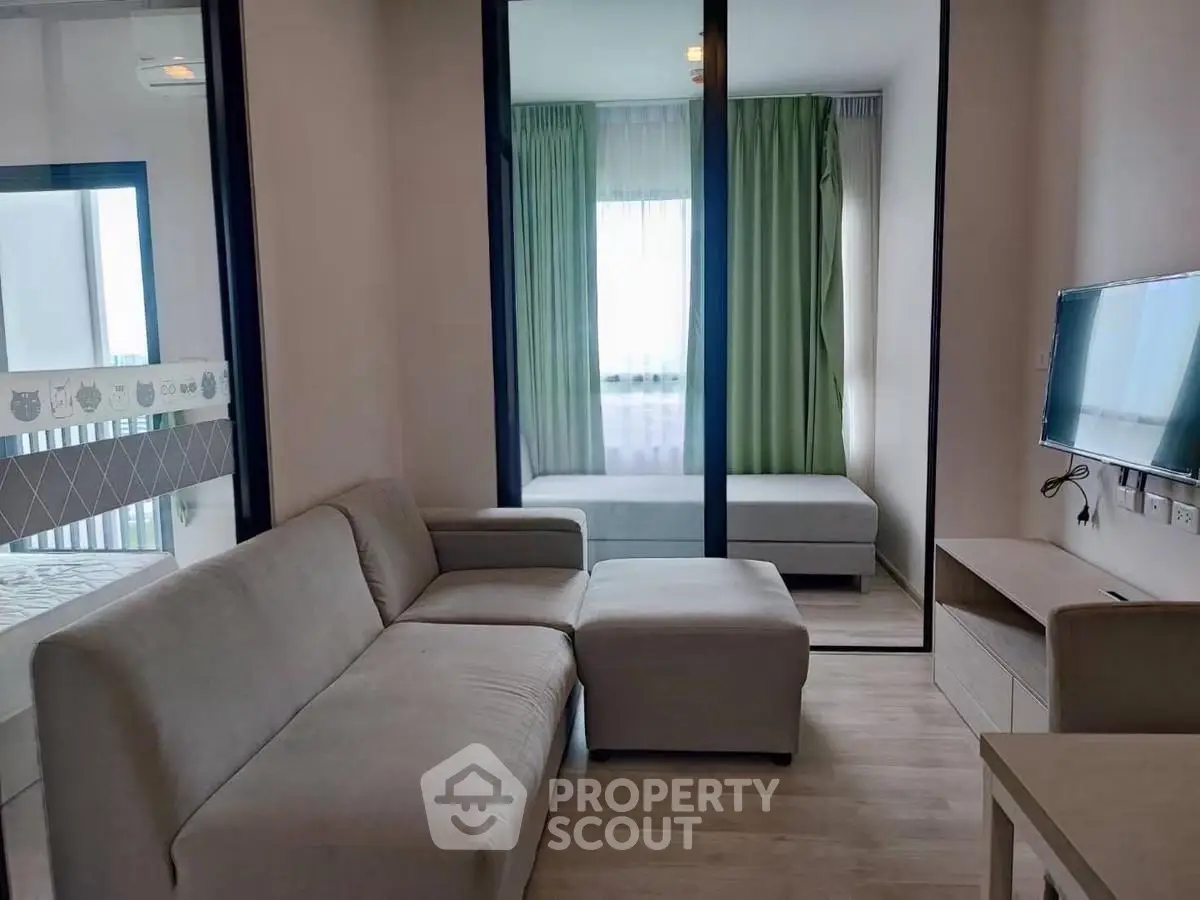 Modern living room with cozy sofa and TV, featuring a stylish glass partition and natural light.