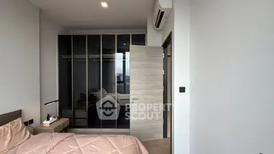 Modern bedroom with sleek glass wardrobe and cozy bedding in a stylish apartment.