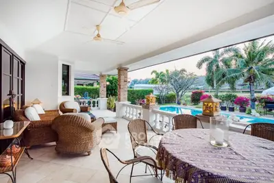 Luxurious patio with pool view, wicker furniture, and tropical garden setting.
