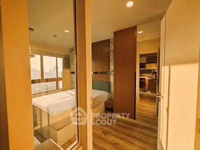 Modern apartment interior with cozy bedroom and open kitchen layout, featuring wooden flooring and natural light.