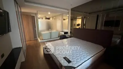 Modern bedroom with mirrored walls and frosted glass bathroom, featuring a sleek design and cozy ambiance.
