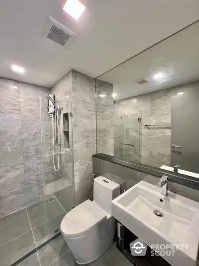 Sleek modern bathroom with marble tiling, glass shower enclosure, and contemporary fixtures, perfect for a luxurious urban living experience.