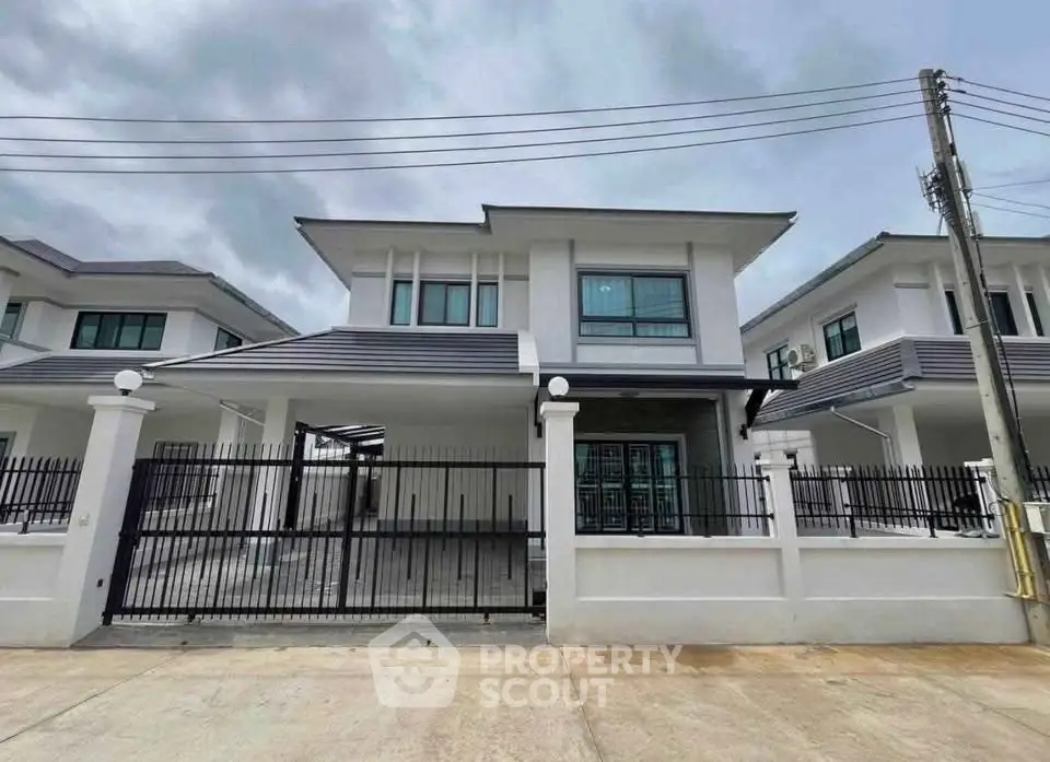 Modern two-story house with sleek design and gated entrance in a suburban neighborhood.