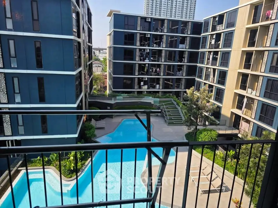 Modern apartment complex with pool view from balcony, showcasing contemporary architecture and lush landscaping.