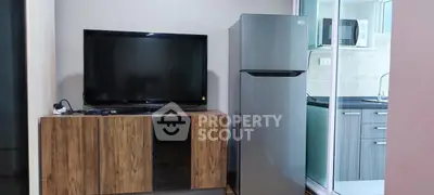 Modern living area with TV, fridge, and kitchen view