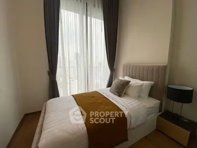 Cozy bedroom with elegant decor and large window offering city views.