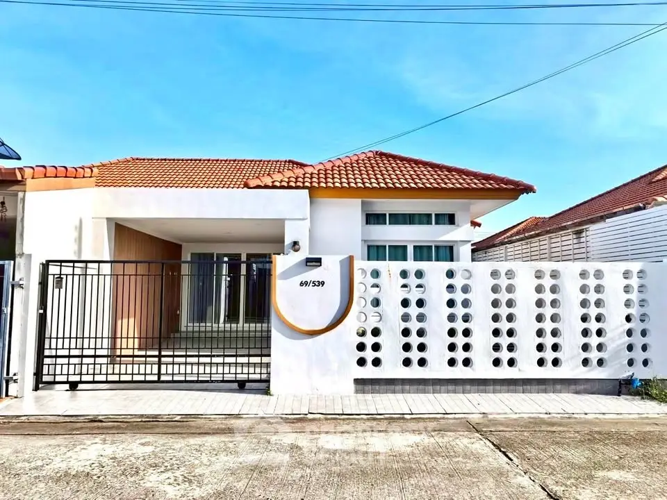 Charming single-story home with modern facade and gated entrance, featuring a stylish roof and spacious driveway.