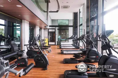 Luxurious gym with modern equipment and floor-to-ceiling windows in upscale building.