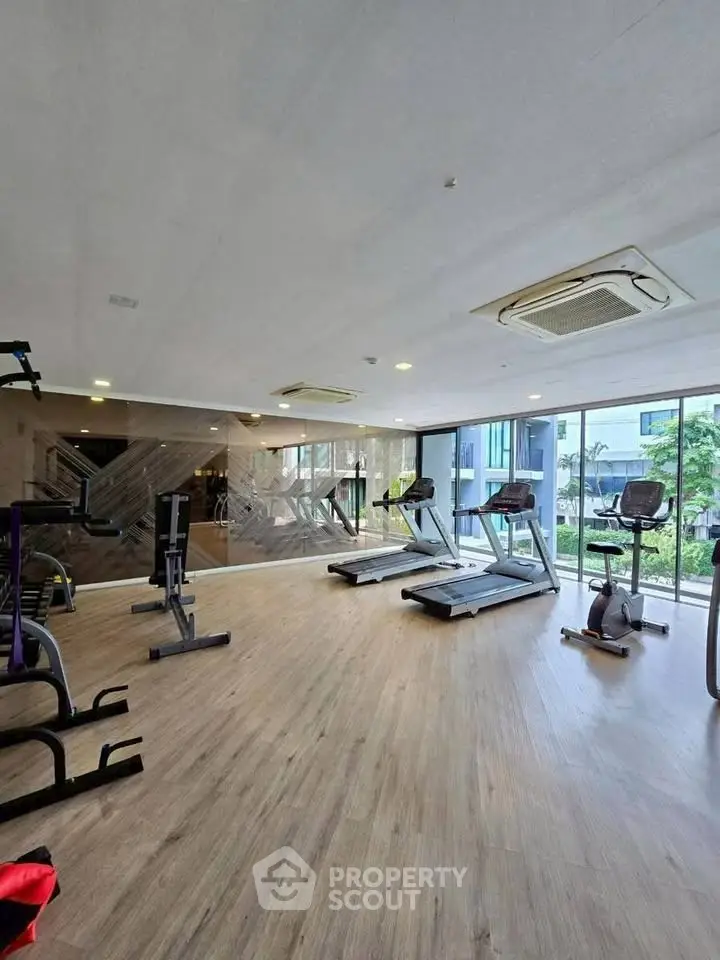 Spacious modern gym with state-of-the-art equipment and large windows for natural light.