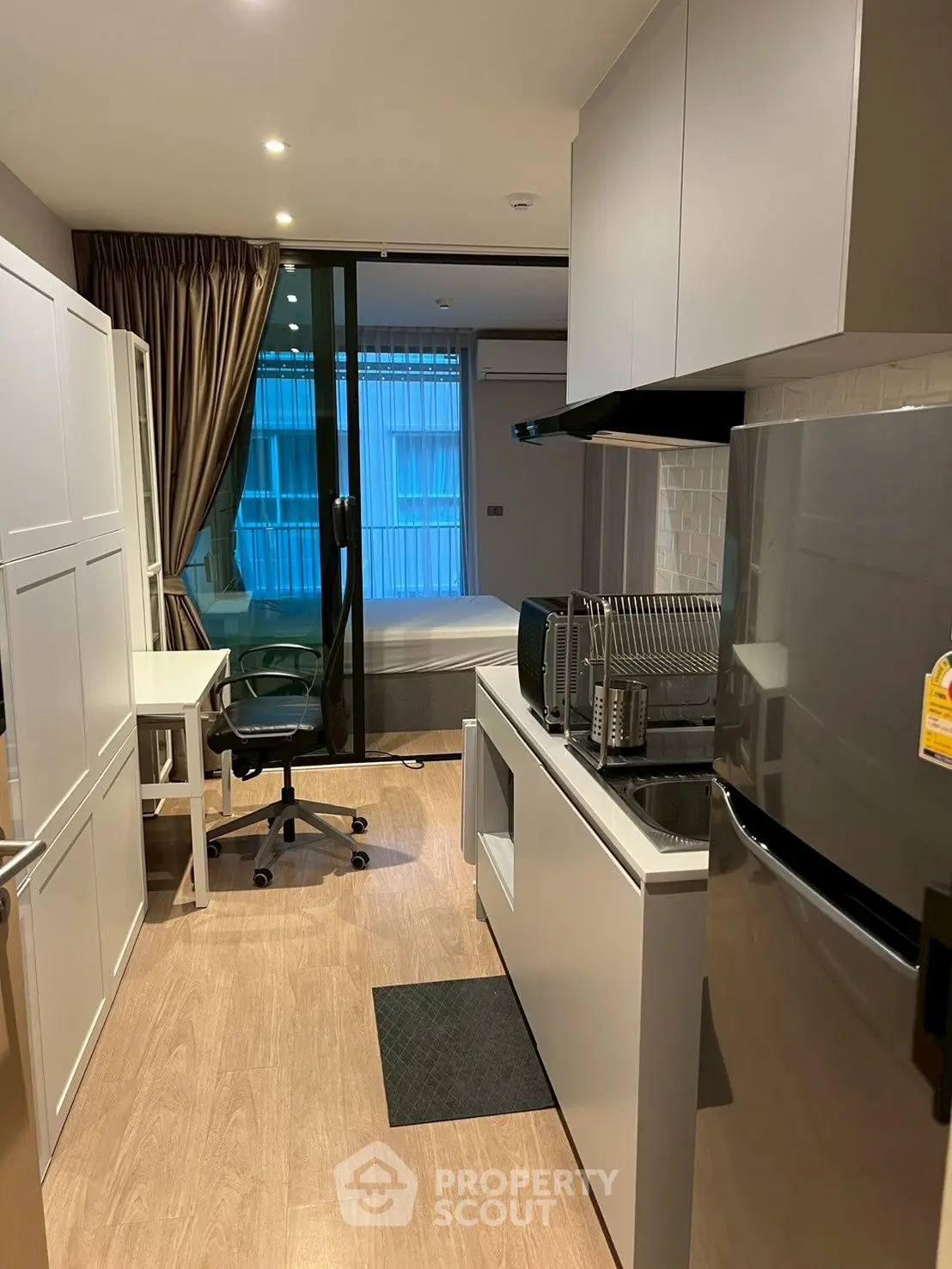 Modern studio apartment with sleek kitchen and cozy bedroom area, perfect for urban living.