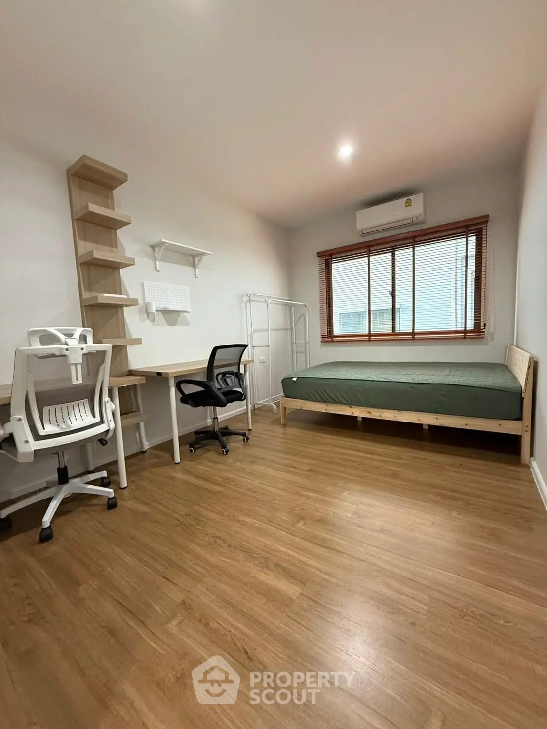 Spacious bedroom with modern furniture and wooden flooring, featuring a desk and comfortable chair.