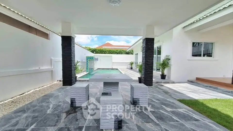 Modern outdoor patio with stylish seating and pool view in a luxurious home setting.